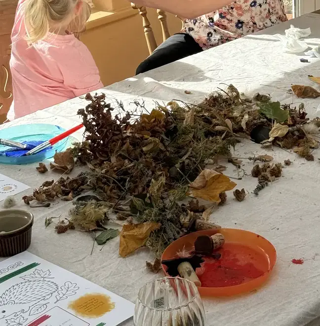 Autumn leaves, paint and brushes spread across the craft table
