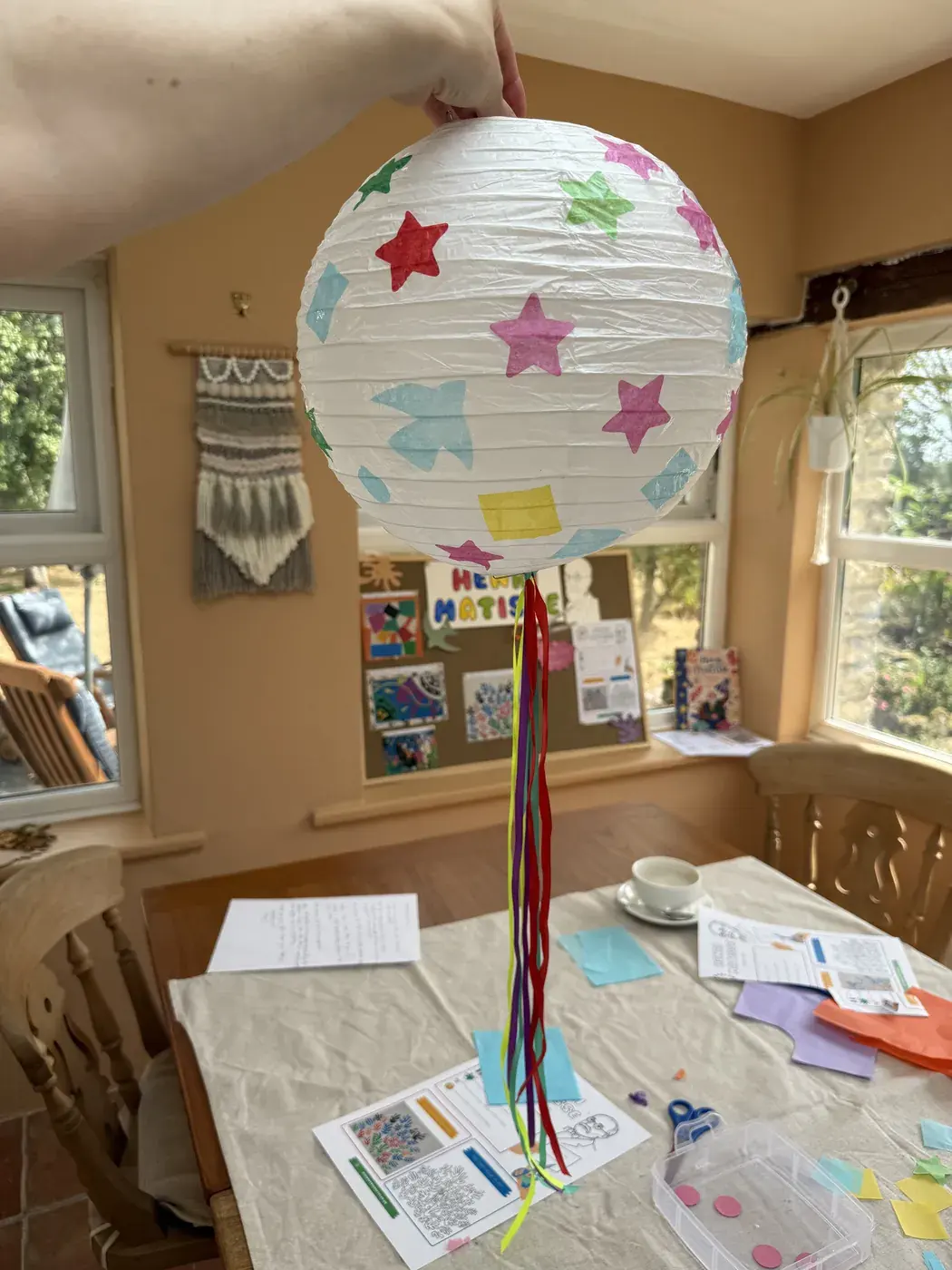 A finished paper lantern decorated with stars, hanging in the room