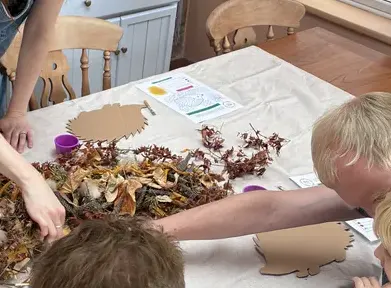 Hands sorting autumn leaves onto cardboard hedgehogs