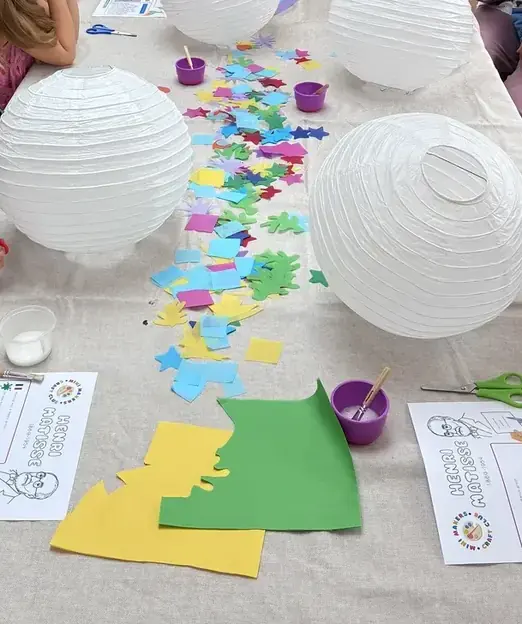 Paper lanterns and coloured paper shapes laid out along the table