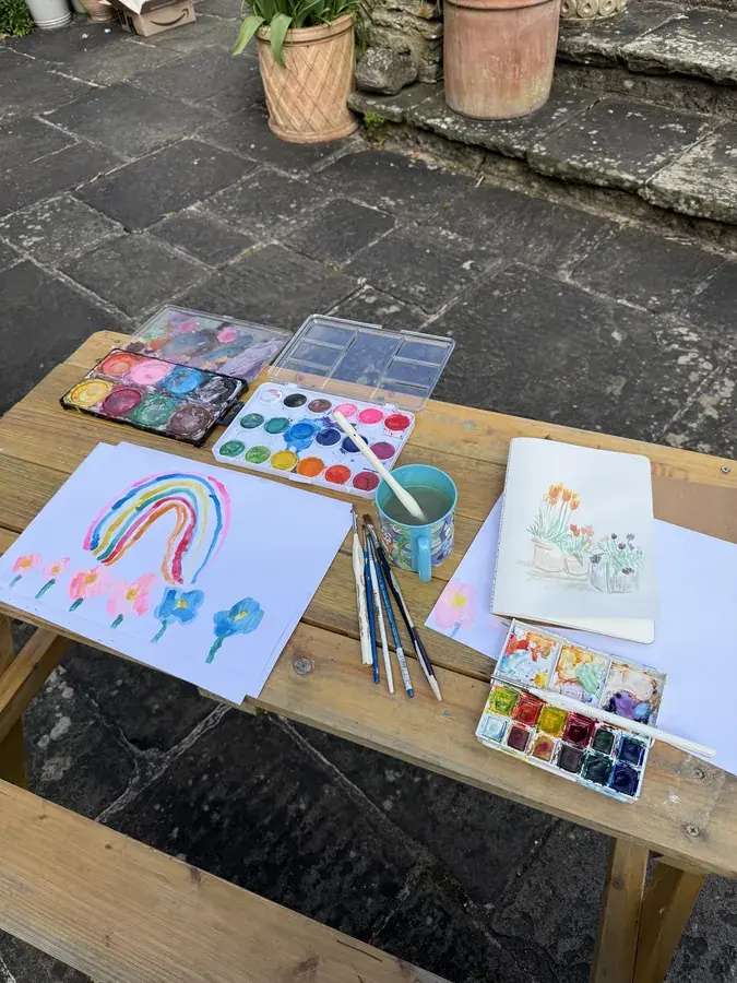 Watercolour palettes, brushes and a painted rainbow on an outdoor table